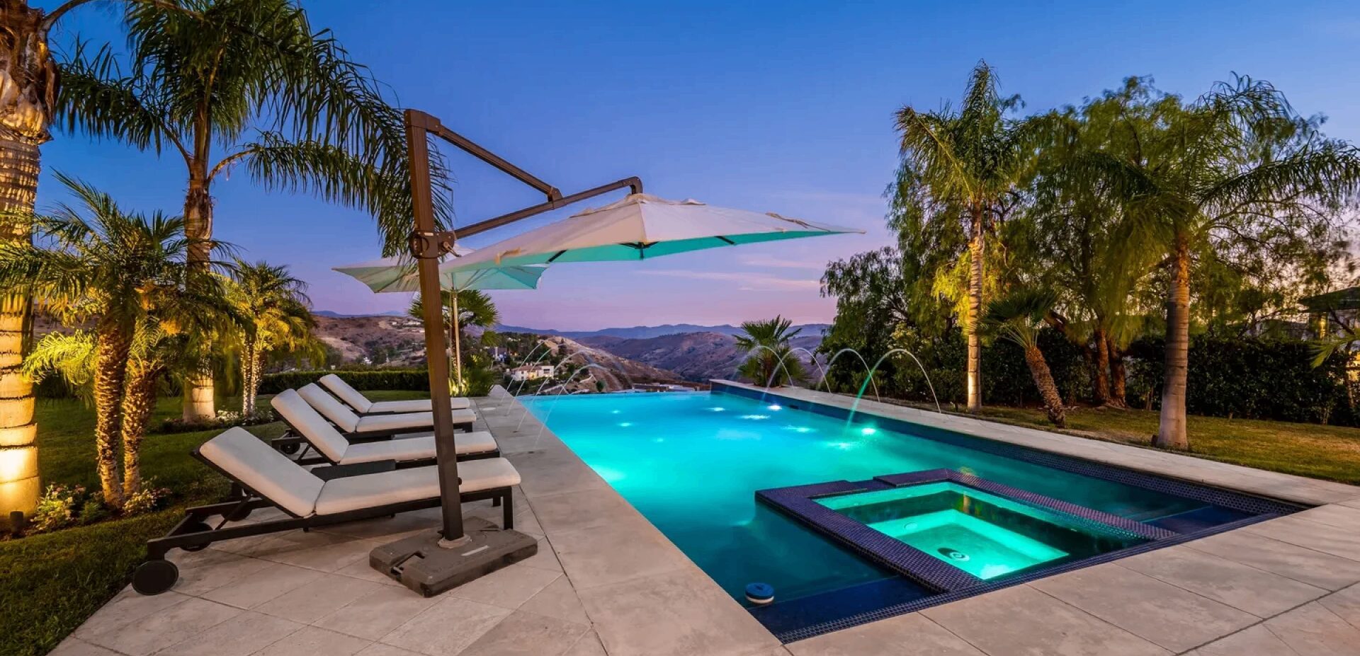 Luxury poolside with loungers and umbrella.